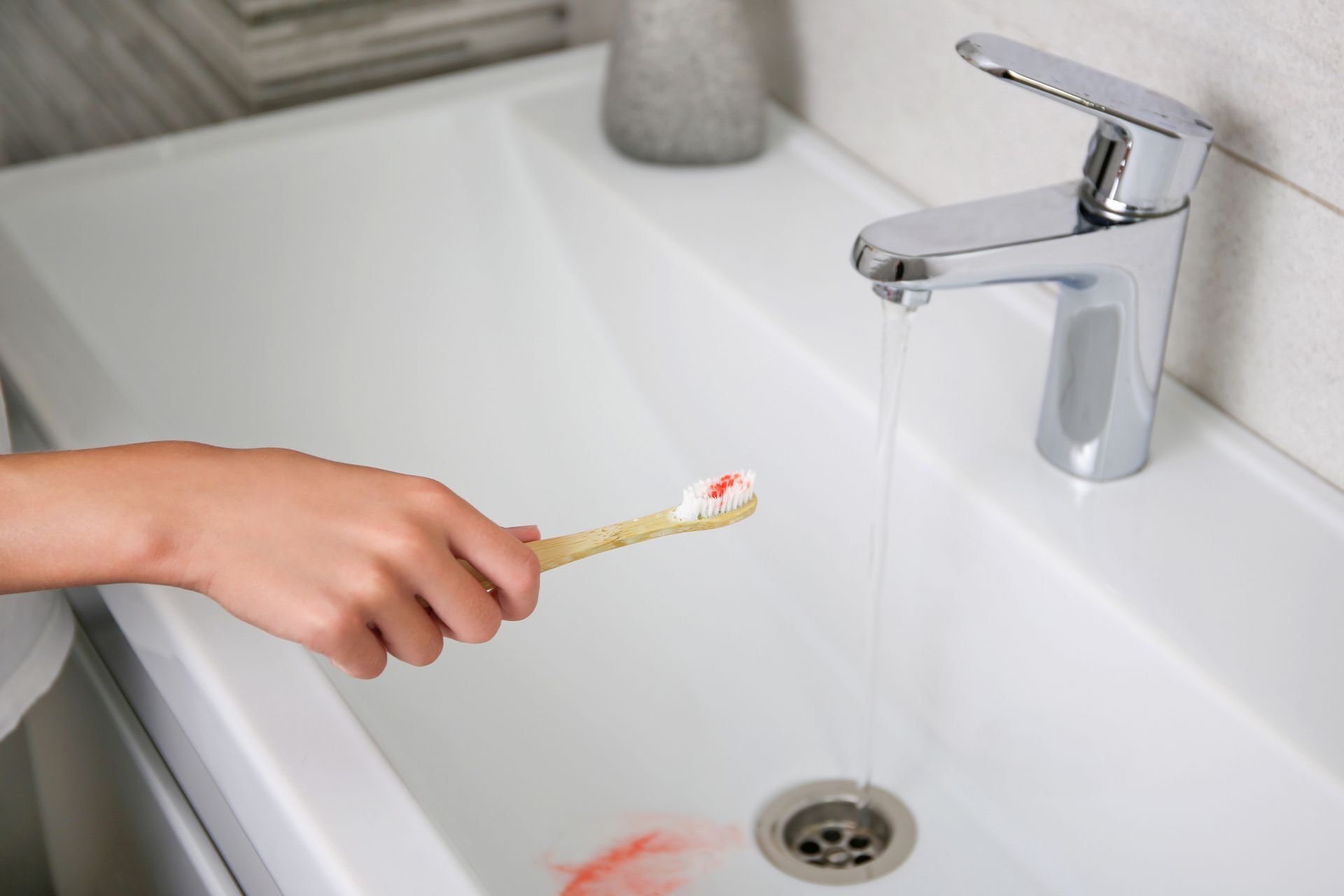 Blut auf der Zahnbürste auf dem Hintergrund des Waschbeckens.