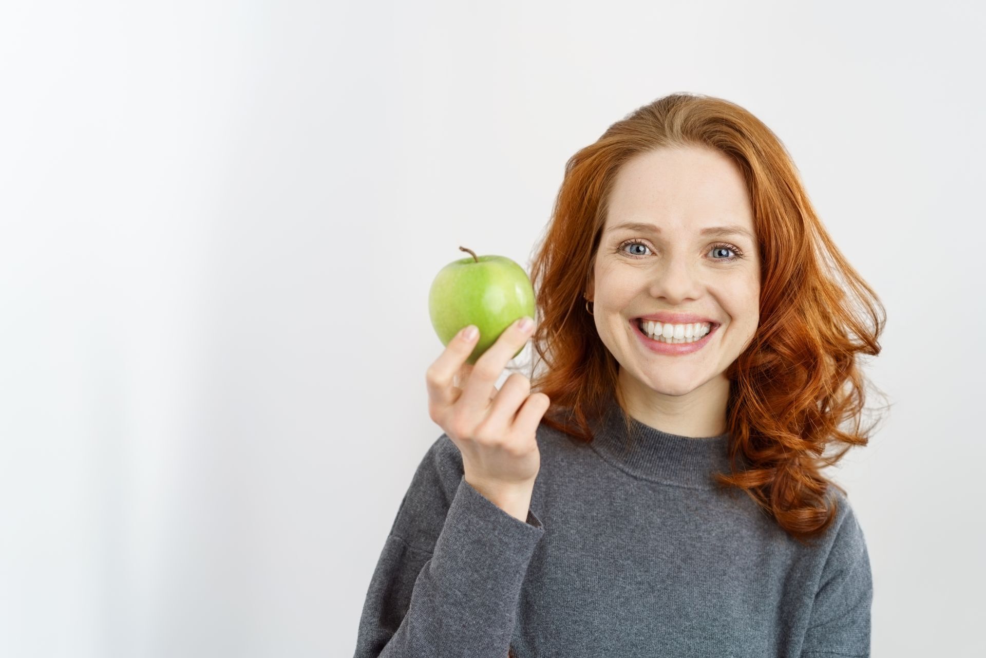 Lächelnde junge Frau mit einem grünen Apfel